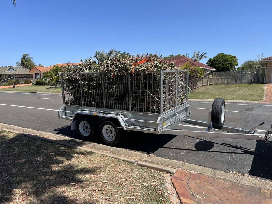 A tandem trailer loaded high with cut branches and garden waste