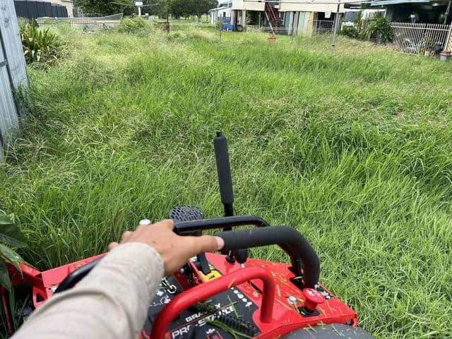 Long grass ahead of a mower being pushed across a block