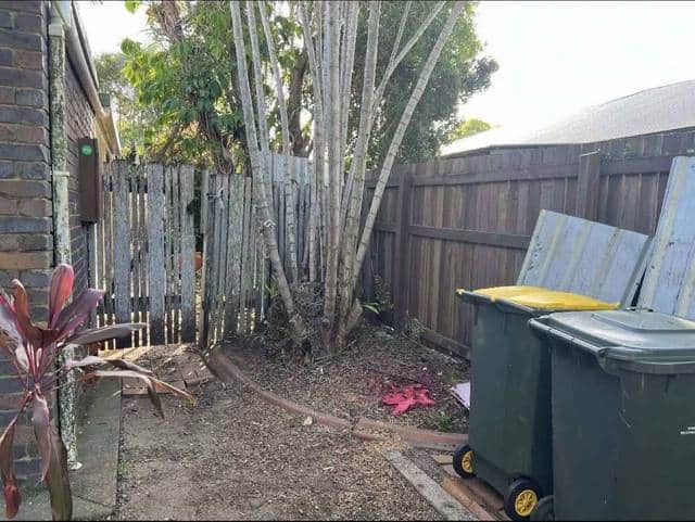 A cleared side yard beside a timber fence with the bins moved back